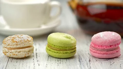 Three sweet macaroon cakes on the table. White and orange, green, pink cakes Stock Footage 132333315