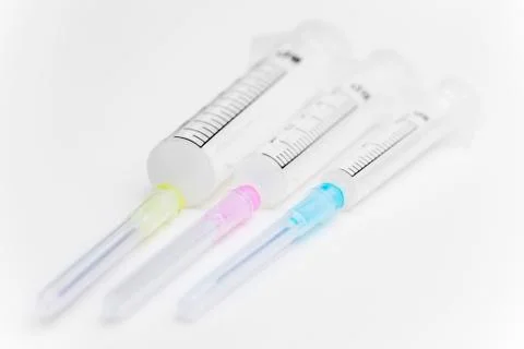Three syringes in different sizes an colors on white background used as medic Stock Photos