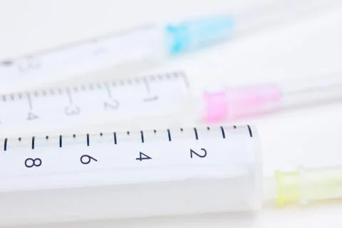 Three syringes in different sizes an colors on white background used as medic Stock Photos