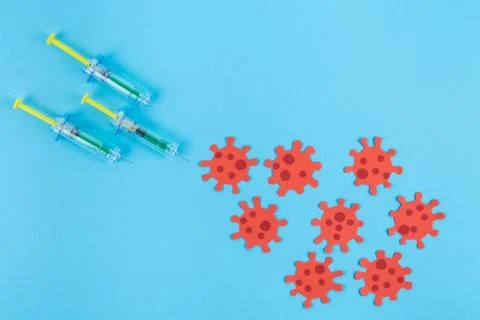 Three syringes stinging a group of red viruses. Copy space. Concept Covid-19. Stock Photos