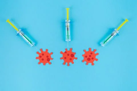 Three syringes stinging three red viruses. Concept Covid-19. Stock Photos