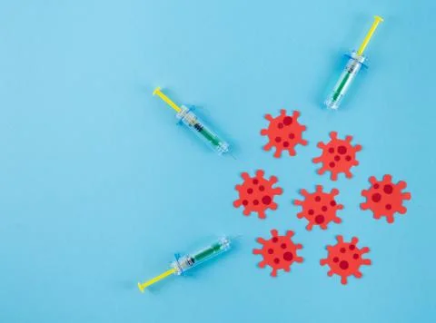 Three syringes surrounding virus clusters on a blue background. Copy space. C Stock Photos