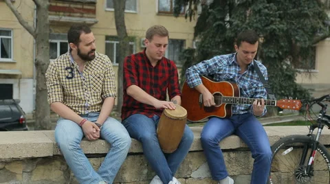 Three talented young guys playing musical instruments and sing a song  Stock Footage 50679957