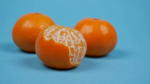 Three tangerines on blue background. Stop motion animation of mandarin peel Stock Footage 121093236