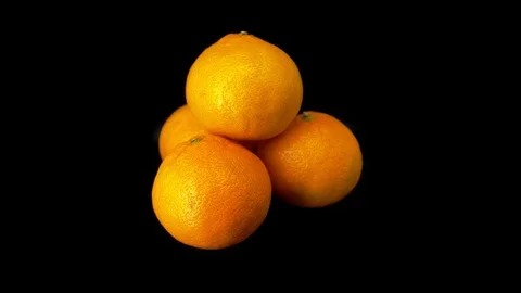 Three tangerines rotate on a black background. . Close-up. Stock Footage 118964636
