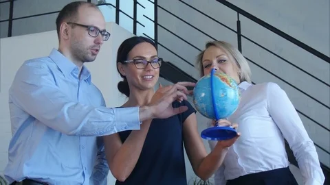 Three teachers discuss something with globe Vídeos de archivo 77424789