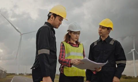 Three technician engineer in uniform with standing and checking wind turbine Foto stock