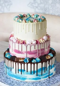 Three-tiered colored cake with colored smudges of chocolate on a light backgr Stock Photos