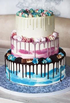 Three-tiered colored cake with colored smudges of chocolate on a light backgr Stock Photos