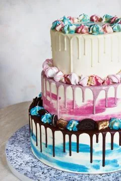 Three-tiered colored cake with colored smudges of chocolate on a light backgr Stock Photos