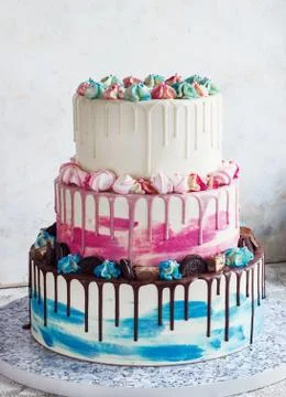 Three-tiered colored cake with colored smudges of chocolate on a light backgr Stock Photos