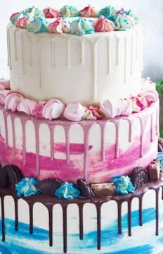 Three-tiered colored cake with colored smudges of chocolate on a light backgr Stock Photos