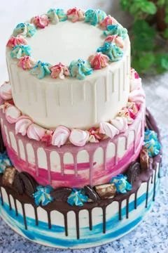 Three-tiered colored cake with colored smudges of chocolate on a light backgr Stock Photos