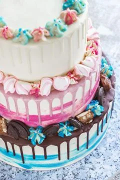 Three-tiered colored cake with colored smudges of chocolate on a light backgr Stock Photos