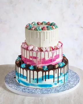 Three-tiered colored cake with colored smudges of chocolate on a light backgr Stock Photos