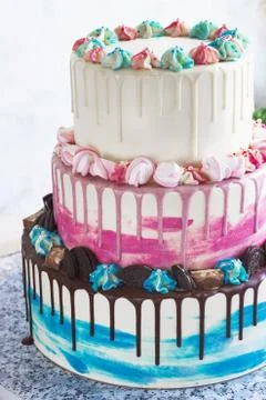 Three-tiered colored cake with colored smudges of chocolate on a light backgr Stock Photos