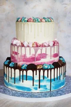 Three-tiered colored cake with colored smudges of chocolate on a light backgr Stock Photos