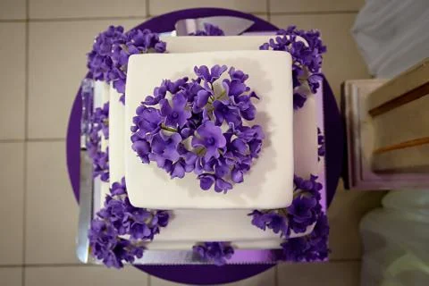 Three-tiered white cake with purple flowers Stock Photos
