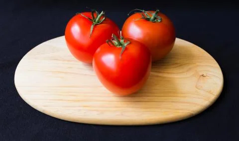 Three tomatoes on a cutting board Stock Photos