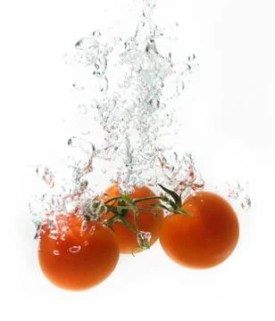 Three tomatoes falling into water - studio isolated. Stock Photos