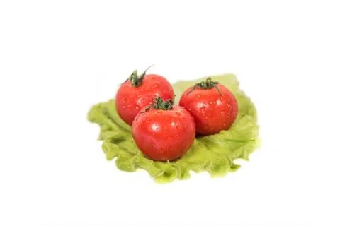 Three tomatoes lying on a sheet of green salad Stock Photos
