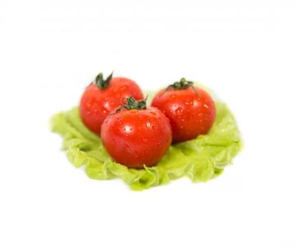 Three tomatoes lying on a sheet of green salad Stock Photos