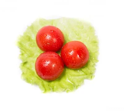 Three tomatoes lying on a sheet of green salad Stock Photos