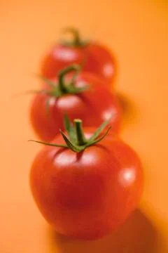 Three tomatoes on orange background Stock Photos