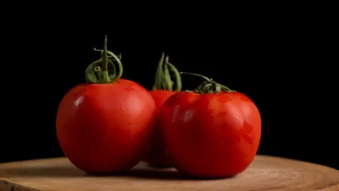 Three Tomatoes Turning in Dark Black Background Stock Footage 284280584
