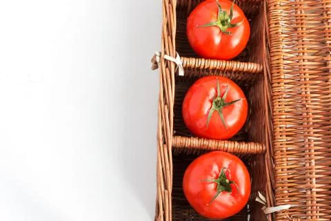 Three tomatoes in wicker box Stock Photos
