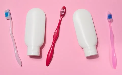 Three toothbrushes and two white plastic tubes of toothpaste placed on a pi.. 스톡 사진