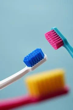 Three toothbrushes on a blue background close-up. Advertising of oral hygiene Stock Photos