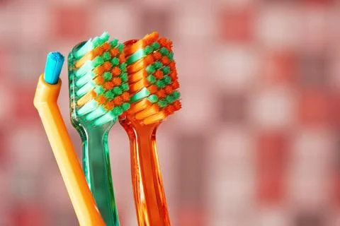 Three toothbrushes with different colored bristles, showing everyday hygiene Stock Photos