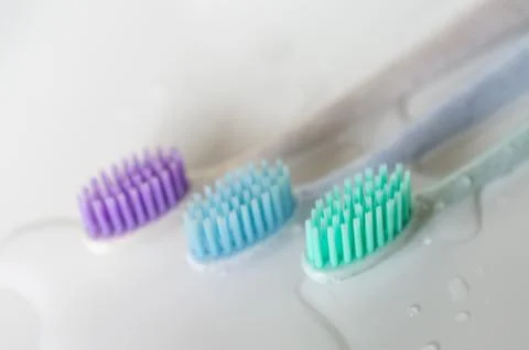 Three toothbrushes of different colors on white background. Stock Photos