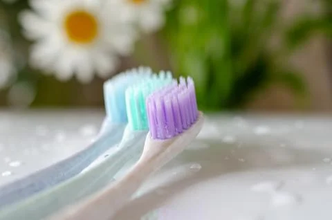 Three toothbrushes of different colors on white background. Stock Photos