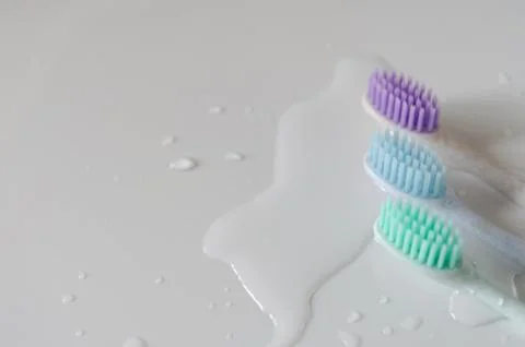 Three toothbrushes of different colors on white background. Stock Photos