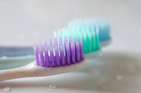 Three toothbrushes of different colors on white background. Stock Photos