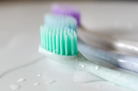 Three toothbrushes of different colors on white background. Stock Photos