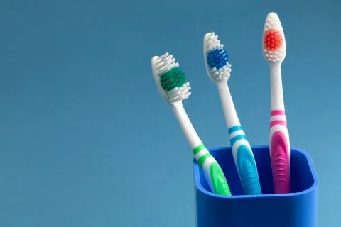 Three toothbrushes stand in a cup Stock Photos