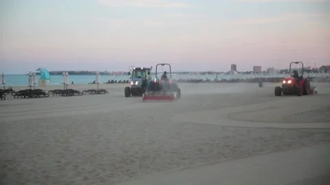 Three tractors cleaning an empty beach in the evening Stock Footage 303514340