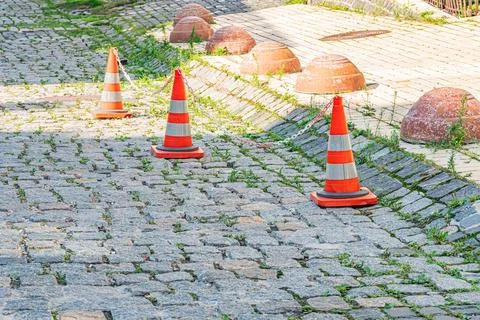 Three traffic cones with reflective stripes orange, white on a cobblestone st Stock Photos