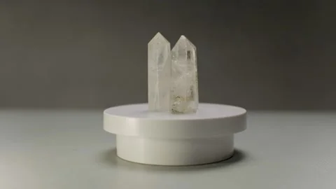Three translucent elongated white crystals rotate on a round stand Stock Footage 305622794