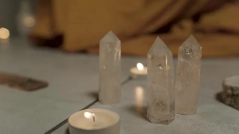 Three transparent cone-shaped crystals stand on the floor among the candles Stock Footage 305402250