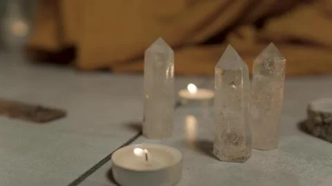 Three transparent cone-shaped crystals stand on the floor among the candles Stock Photos