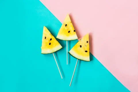 Three triangular ice cream slices on a stick of ripe yellow watermelon 스톡 사진