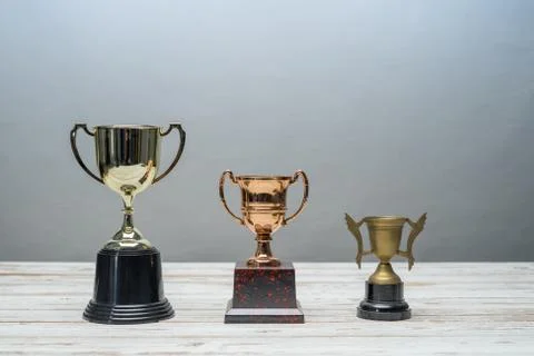 Three trophy with difference size and design on vintage wooden table.Step or  Stock Photos