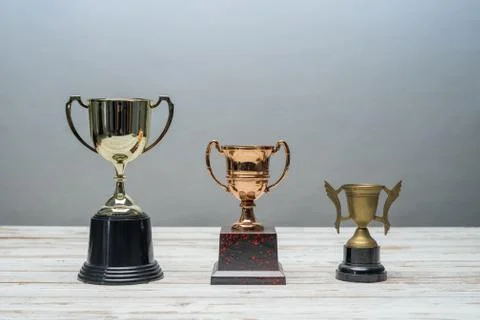 Three trophys with difference size and design on vintage wooden table.Step or Stock Photos
