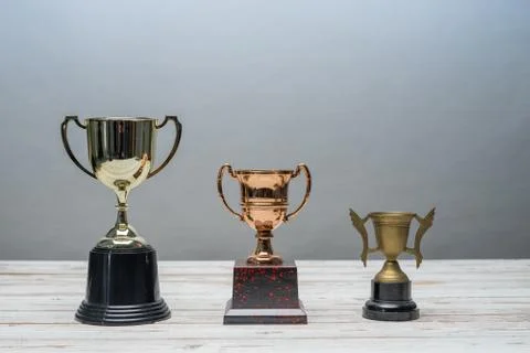 Three trophys with difference size and design on vintage wooden table.Step or 스톡 사진