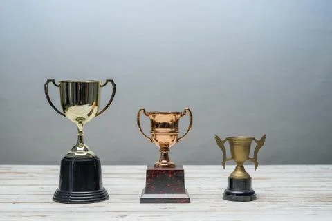 Three trophys with difference size and design on vintage wooden table.Step or Stock Photos