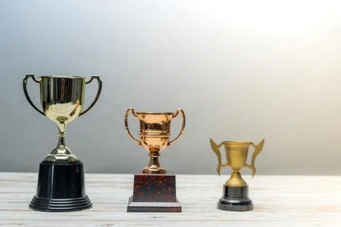 Three trophys with difference size and design on vintage wooden table.Step or Foto stock